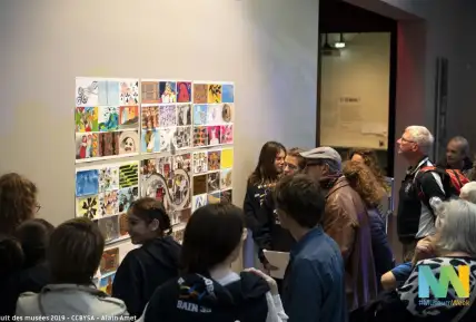 Une photographie d'un groupe de personnes devant un assemblage de dessins.