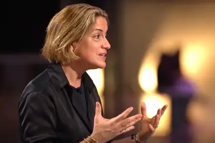 Emilie Aubry sur le plateau de l'émission. Elle est assise et parle avec ses mains.