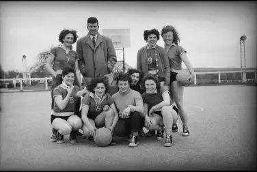 Une équipe de huit joueuses de basket avec leur dirigenat sourit à l'objectif