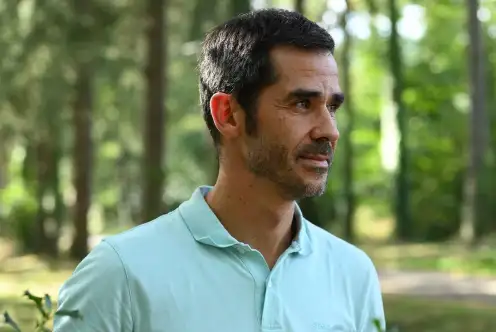 Dans une clairière, Antonhy Berthou se tient debout, les mains dans les poches. Il porte un polo bleu clair.