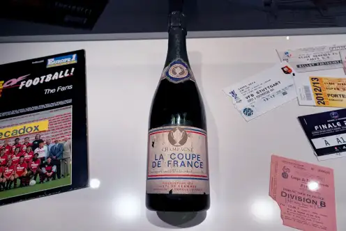 Une photo d'une bouteille de champagne marquée de l'inscription "La coupe de France", et d'autre objets en lien avec le football