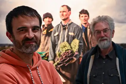 Devant une des photographies du Musée d'agriculteurs dans un champs Nicolas Legendre (à gauche) et Yvon Le Caro (à droite) posent en souriant. NC posent un sweat à capuche orange, et YLC une veste bleue marine.