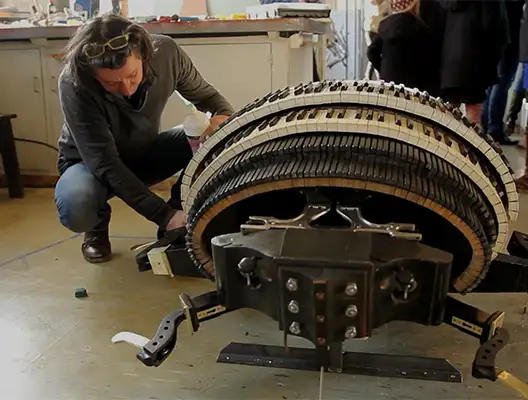 Une photographie d'un homme en train de travailler sur une structure en forme de scarabée, donc la carapace est une série de touches de piano.