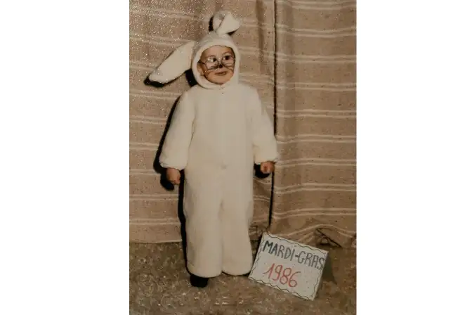 Photographie d'un enfant déguisé dans un costume de lapin. L'enfant est maquillé. A ses pieds, un panneau avec écrit "Mardi gras 1986"