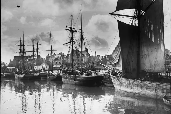 Prise de vue en noir et blanc de bateaux en bois amarés au port.