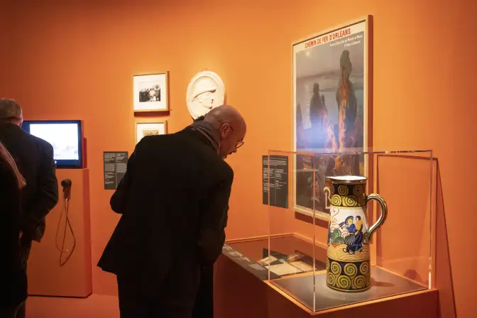 Week-end d'inauguration de l'exposition Celtique ?. Devant un mur orange, un homme observe des éléments de l'exposition.