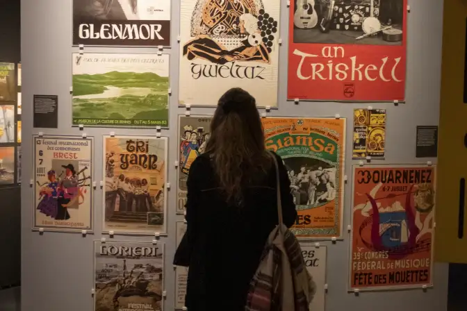 Week-end d'inauguration de l'exposition Celtique ?. Un mur d'affiche est observé par une femme que l'on voit de dos.