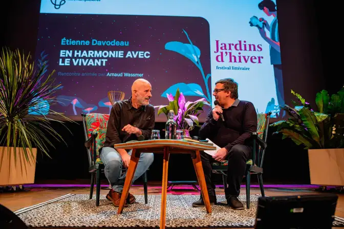 Sur la scène de l'Auditorium, entourés de plantes, assis devant une petite table, l'auteur Etienne Davodeau discute avec l'animateur Arnaud Wassmer.