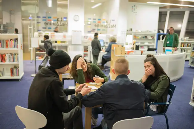 Une photographie de la Mezzanine, un groupe de jeunes personnes joue aux cartes sur l'une des tables à disposition.