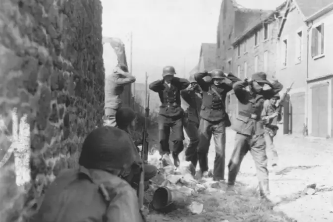 Les soldats allemands avancent, les mains sur la tête, entre deux rangs de soldats américains armés.