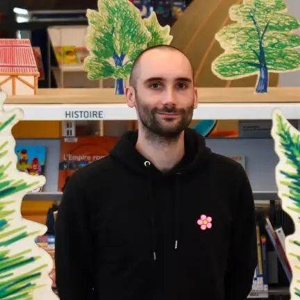 Une photographie de Valérian Henry qui sourit devant ses dessins réalisés pour l'installation participative L'Ouest fantastique à la Bibliothèque des Champs Libres.