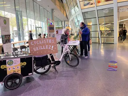 Des personnes échangent autour d'un stand de présentation dans le hall