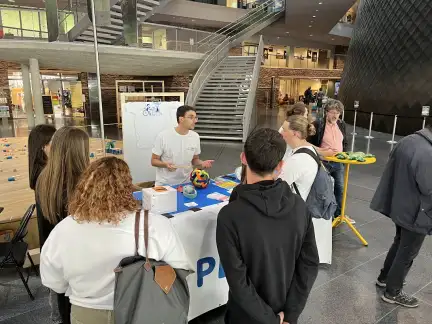 Des personnes échangent autour d'un stand de présentation dans le hall