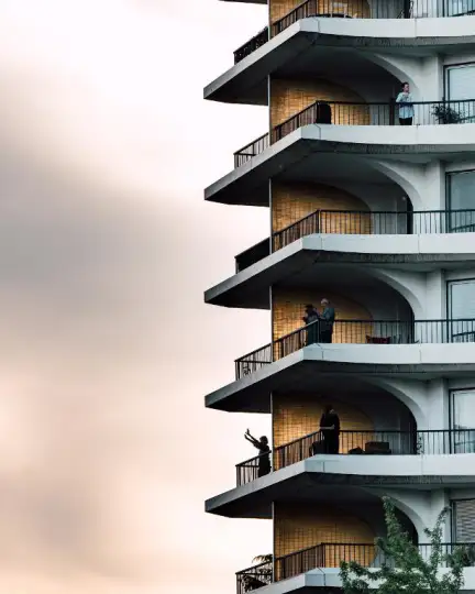 Une photographie de l'immeuble des Horizons, avec six balcons mis en avant. Sur certains de ces balcons, on aperçoit des gens regarder et faire des signes à l'extérieur.