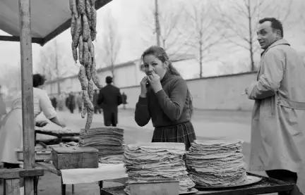 Une jeune fille est en train de manger une galette au stand de la buvette. Elle metrs