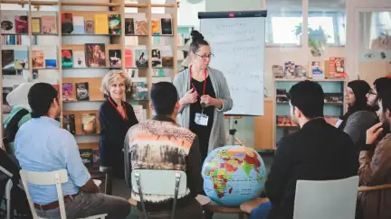 photo où l'on voit un groupe de personnes qui discutent à côté d'un globe terrestre et d'un paperboard