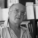 Une photographie en noir et blanc de Francis Hallé devant une bibliothèque.