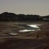 Une photographie prise dans le sud de l'Espagne d'une étendue d'eau. Des montagnes se détachent du fond de l'image et le soleil au crépuscule se reflète dans l'eau.