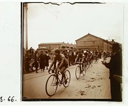 Une image stéréoscopique du Tour de France à Rennes en 1934. Des coureurs à vélo se succèdent à la file indienne devant une foule qui les applaudit.