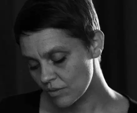 Une photographie portrait en noir et blanc d'une femme aux cheveux courts, le regards baissé.