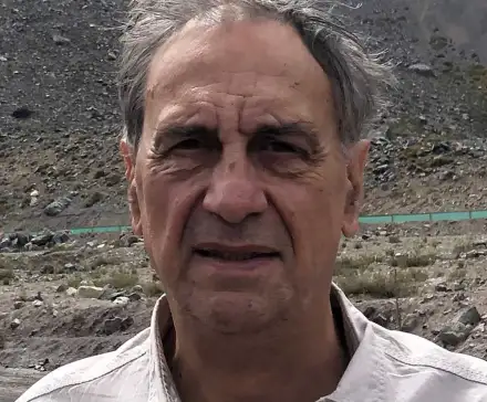 Portrait photographique de Gérard Noiriel, en extérieur, devant un paysage montagneux très sec.