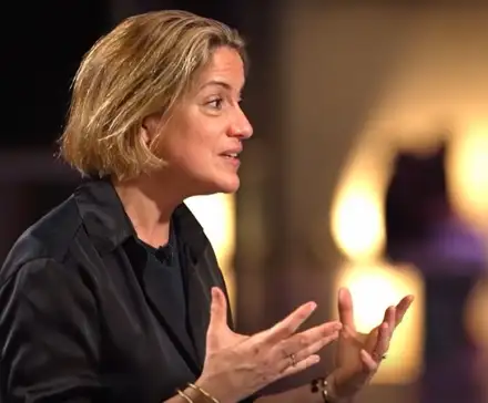 Emilie Aubry sur le plateau de l'émission. Elle est assise et parle avec ses mains.